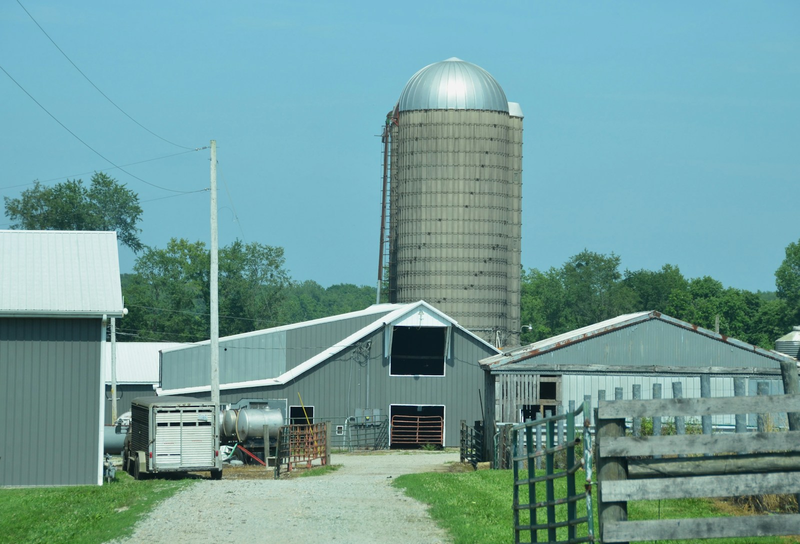 Farm buildings with a silo stand under a blue sky.